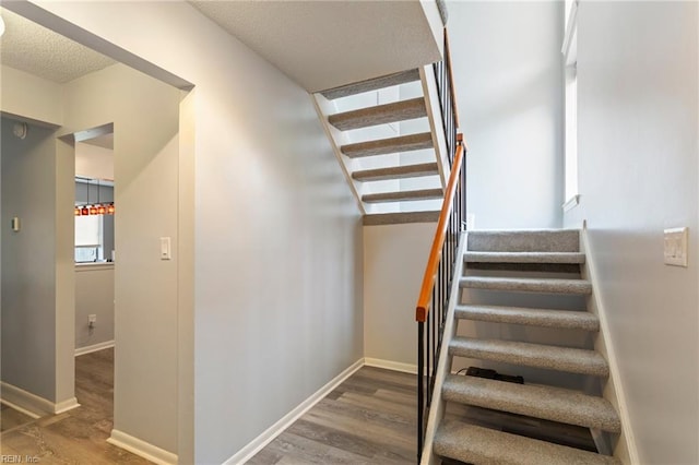 staircase with hardwood / wood-style flooring and a textured ceiling