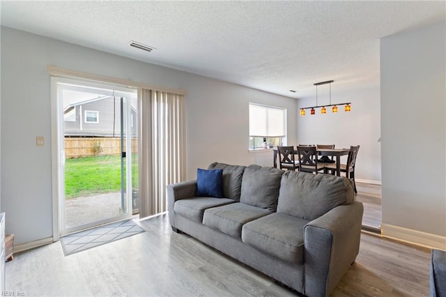 living room with a textured ceiling and light hardwood / wood-style flooring