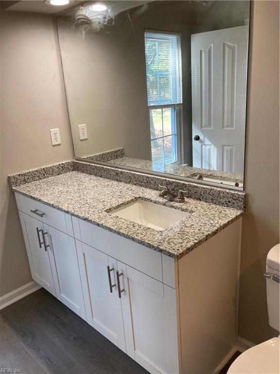 bathroom with hardwood / wood-style flooring, vanity, and toilet