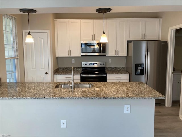 kitchen with sink, pendant lighting, stone countertops, white cabinets, and appliances with stainless steel finishes