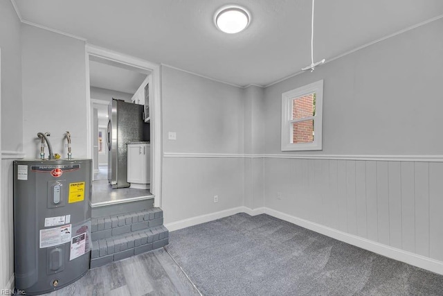 basement with electric water heater, hardwood / wood-style flooring, and stainless steel refrigerator