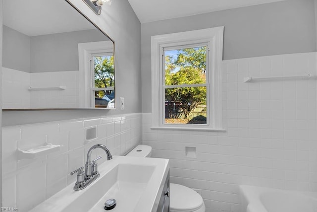 bathroom with vanity, a bathtub, toilet, and tile walls