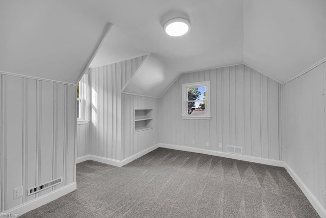 bonus room featuring carpet, built in shelves, and lofted ceiling