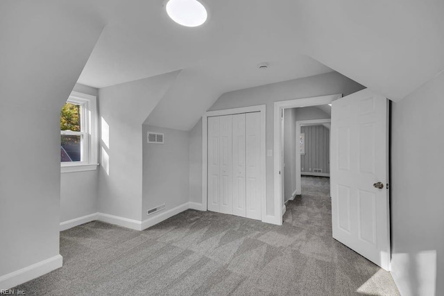 bonus room with light carpet and vaulted ceiling