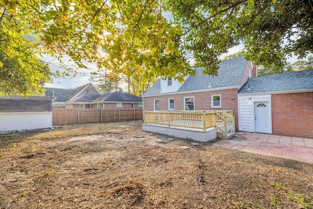 rear view of property featuring a storage shed and a wooden deck