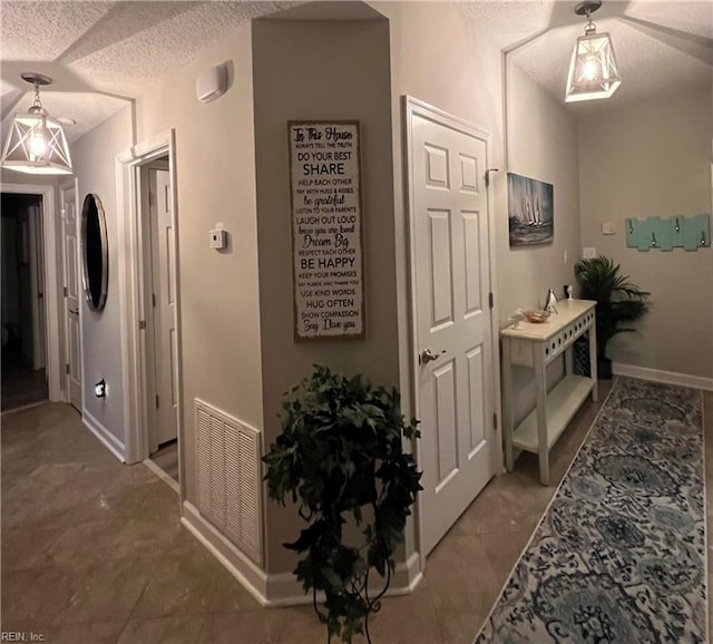 hall with tile patterned floors and a textured ceiling