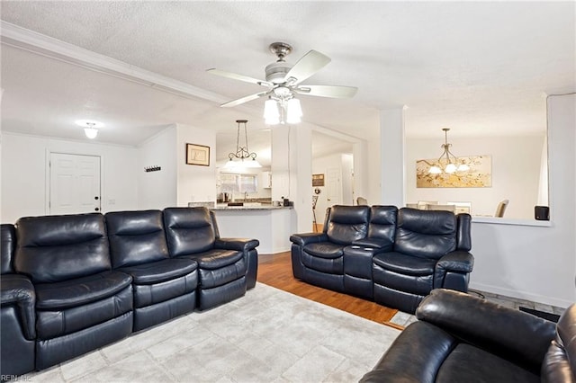 living room featuring a textured ceiling, ceiling fan with notable chandelier, crown molding, and light hardwood / wood-style flooring