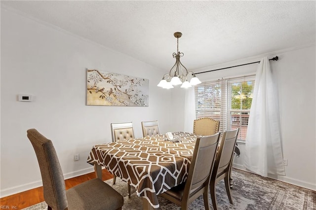 dining area with dark hardwood / wood-style floors, vaulted ceiling, a textured ceiling, and an inviting chandelier