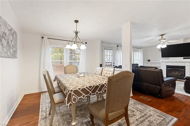 dining area featuring a textured ceiling, ceiling fan with notable chandelier, and dark hardwood / wood-style floors