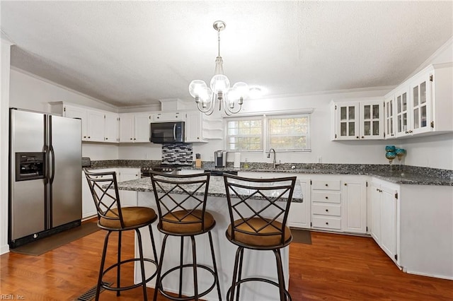 kitchen featuring stainless steel refrigerator with ice dispenser, dark hardwood / wood-style flooring, a center island, white cabinetry, and a breakfast bar area