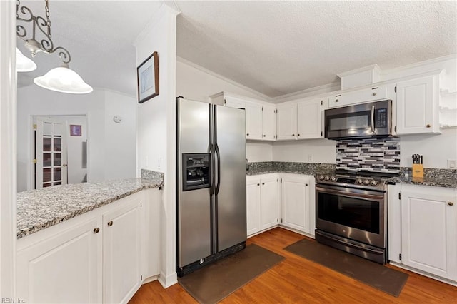 kitchen featuring white cabinets, decorative light fixtures, and appliances with stainless steel finishes