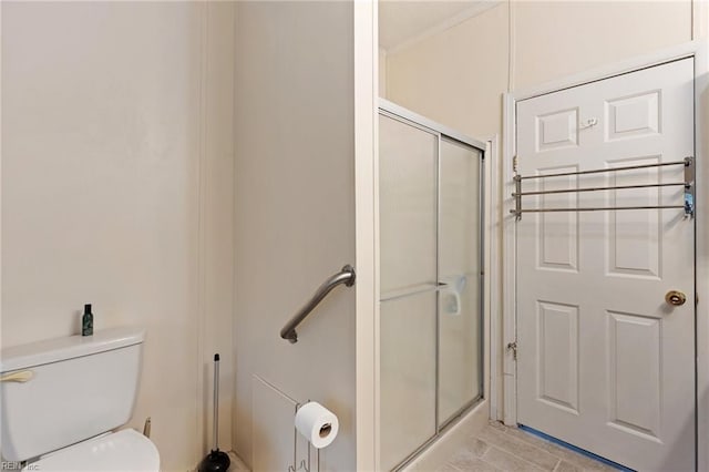 bathroom featuring a shower with shower door and toilet