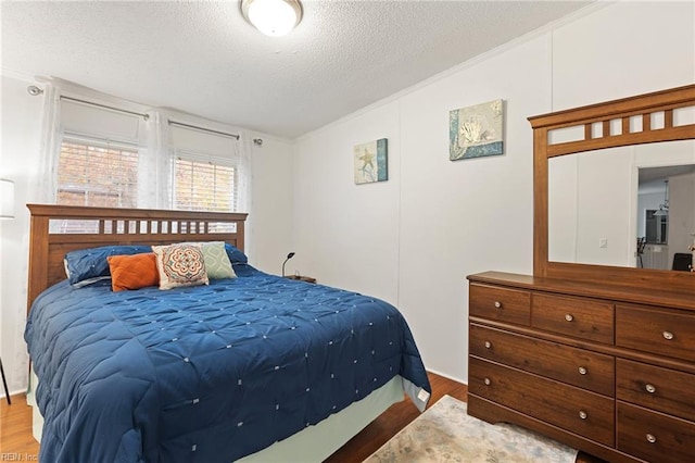 bedroom with lofted ceiling, a textured ceiling, hardwood / wood-style flooring, and crown molding