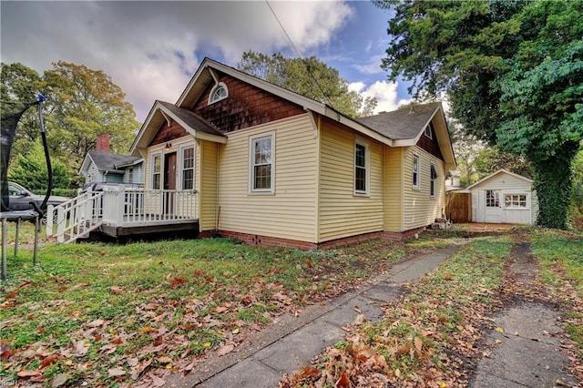 view of side of property featuring a shed, a trampoline, and a wooden deck