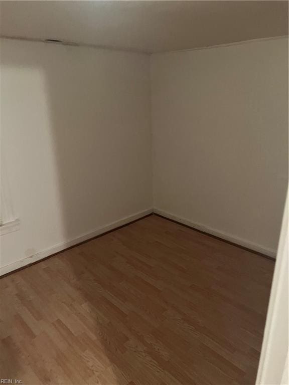 spare room with baseboards and wood finished floors