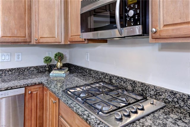 kitchen featuring stainless steel appliances and dark stone counters