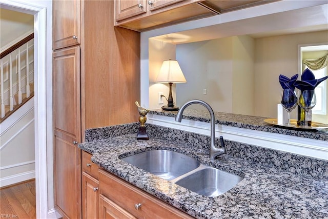 kitchen with wood-type flooring, sink, and dark stone counters