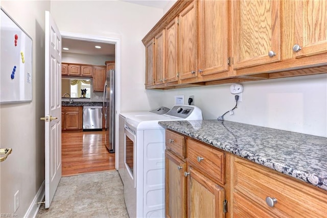 clothes washing area featuring cabinets, light wood-type flooring, and washing machine and clothes dryer