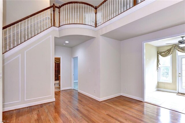 foyer featuring ceiling fan, light wood-type flooring, and a high ceiling