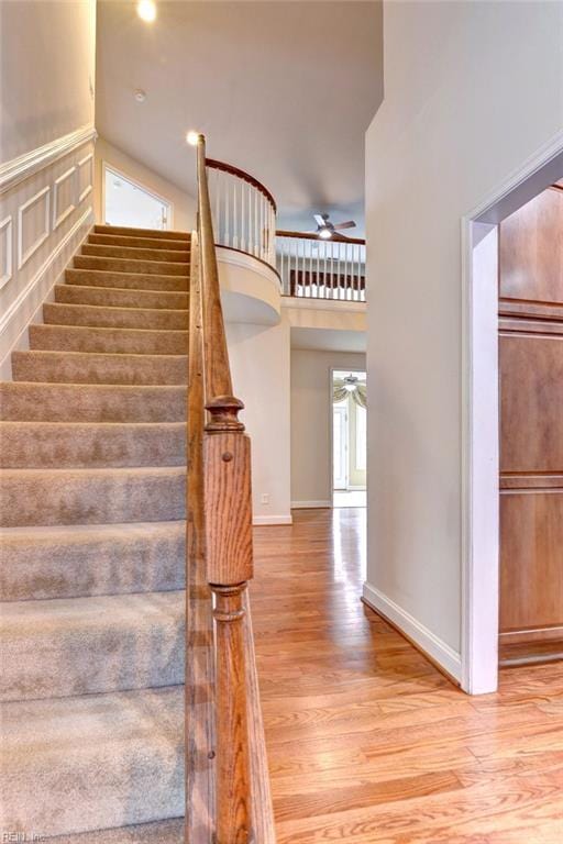 stairs featuring hardwood / wood-style flooring, ceiling fan, and a towering ceiling