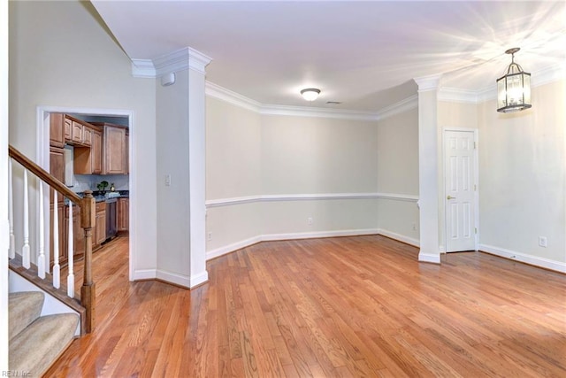 unfurnished room with a chandelier, ornamental molding, and light hardwood / wood-style flooring