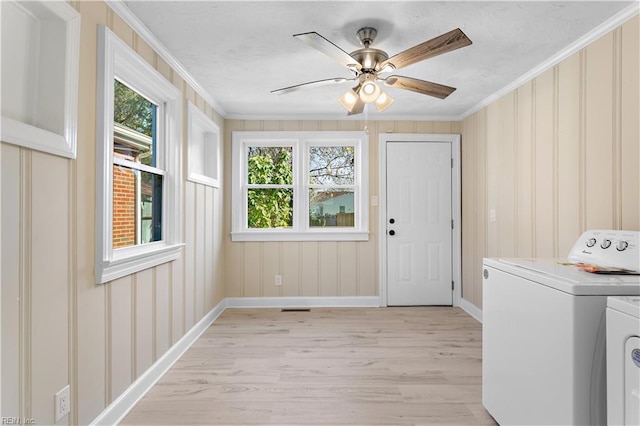 laundry area featuring washer and clothes dryer, plenty of natural light, crown molding, and light hardwood / wood-style flooring