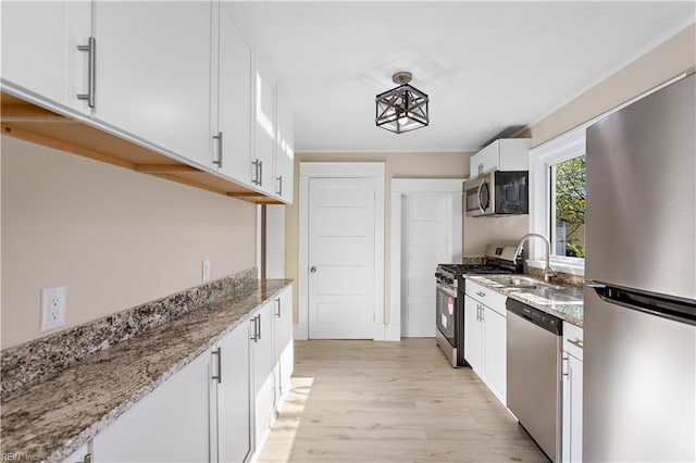 kitchen with light stone countertops, appliances with stainless steel finishes, sink, light hardwood / wood-style floors, and white cabinetry