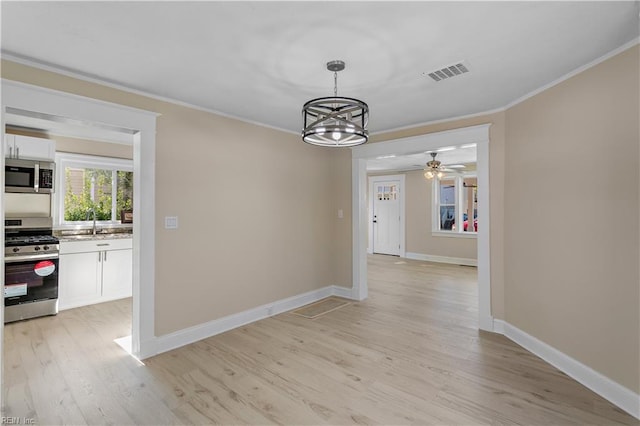 unfurnished dining area featuring sink, ornamental molding, ceiling fan with notable chandelier, and light wood-type flooring