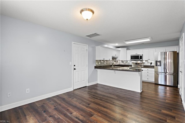 kitchen with kitchen peninsula, dark hardwood / wood-style floors, white cabinetry, and stainless steel appliances