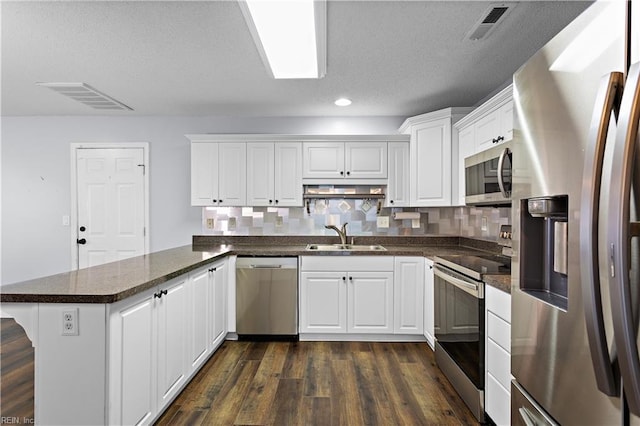 kitchen featuring sink, dark hardwood / wood-style flooring, kitchen peninsula, white cabinets, and appliances with stainless steel finishes