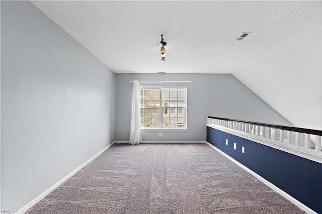 carpeted empty room with a textured ceiling and lofted ceiling