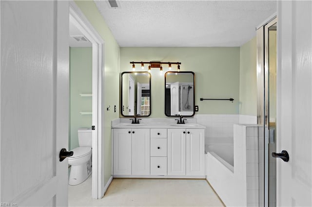 bathroom with vanity, a bath, a textured ceiling, and toilet