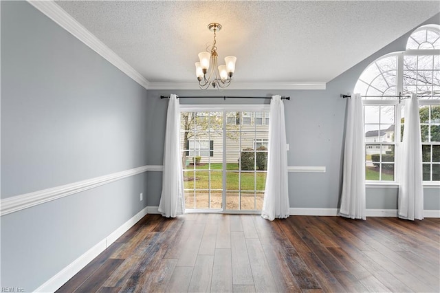 unfurnished dining area featuring a textured ceiling, crown molding, dark wood-type flooring, and a chandelier