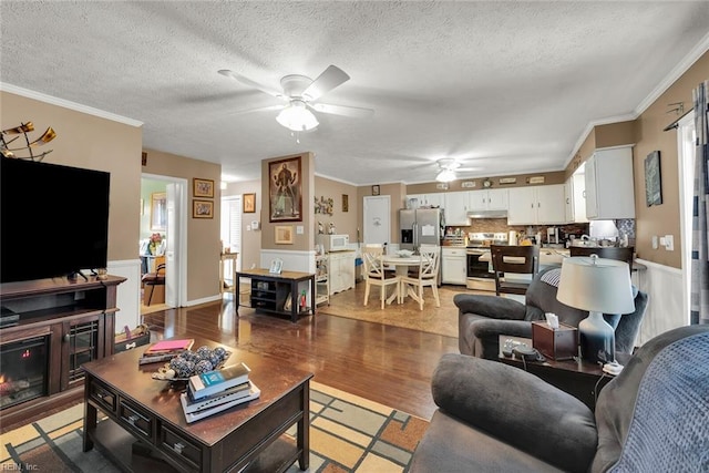 living room with a textured ceiling, hardwood / wood-style flooring, ceiling fan, and ornamental molding