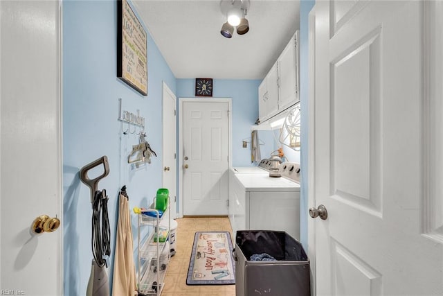 laundry room featuring washing machine and dryer, light tile patterned floors, and cabinets