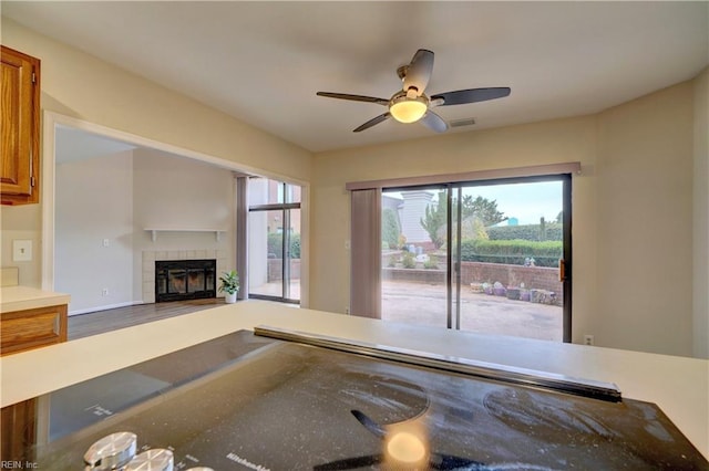 unfurnished living room featuring hardwood / wood-style flooring, ceiling fan, and a tiled fireplace