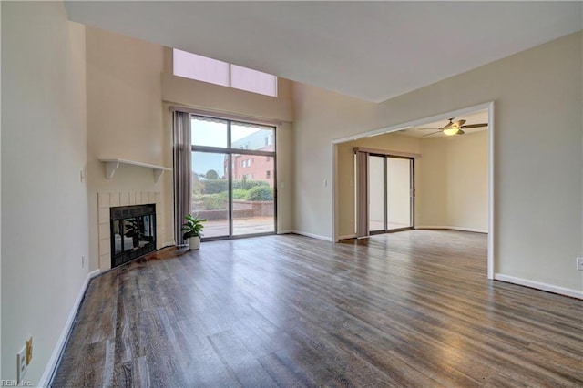 unfurnished living room featuring a tile fireplace, ceiling fan, and dark hardwood / wood-style floors