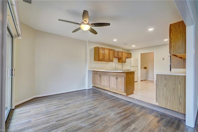 kitchen featuring kitchen peninsula, ceiling fan, sink, white refrigerator, and light hardwood / wood-style flooring