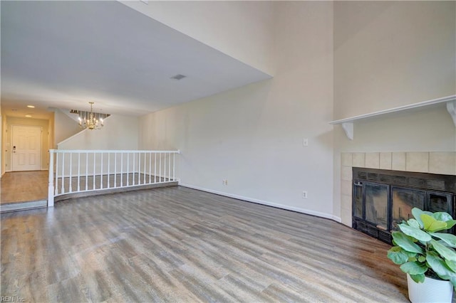 unfurnished living room with a fireplace, hardwood / wood-style floors, and a notable chandelier