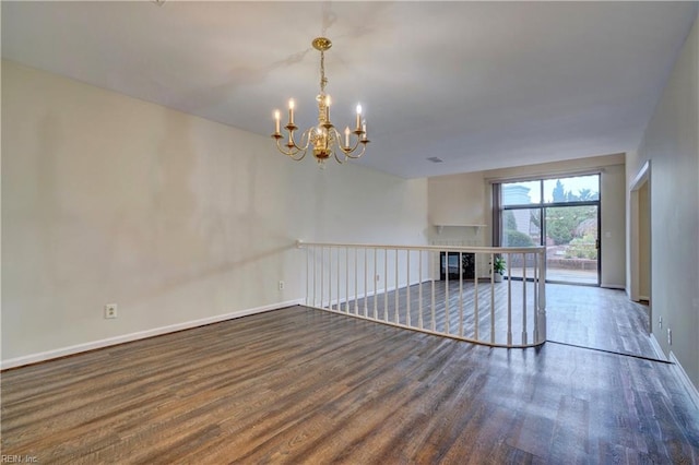 unfurnished living room featuring dark wood-type flooring and a notable chandelier