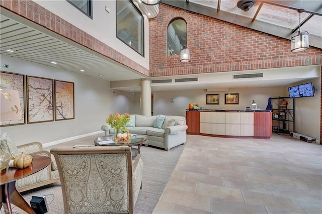 tiled living room featuring a towering ceiling and brick wall