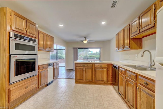 kitchen featuring kitchen peninsula, stainless steel appliances, ceiling fan, sink, and light hardwood / wood-style flooring