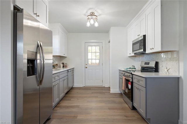 kitchen featuring decorative backsplash, appliances with stainless steel finishes, gray cabinets, and light hardwood / wood-style floors