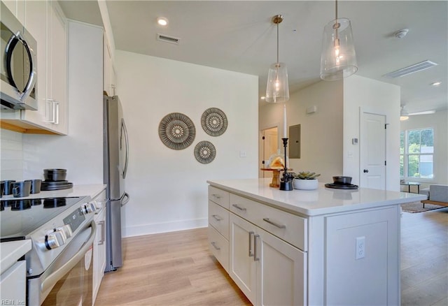 kitchen featuring a kitchen island, appliances with stainless steel finishes, pendant lighting, white cabinets, and light wood-type flooring