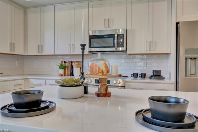 kitchen with backsplash, light stone counters, white cabinetry, and stainless steel appliances