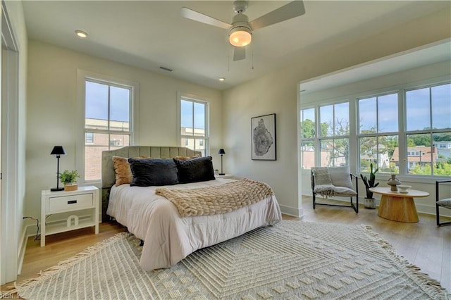 bedroom with light wood-type flooring, multiple windows, and ceiling fan