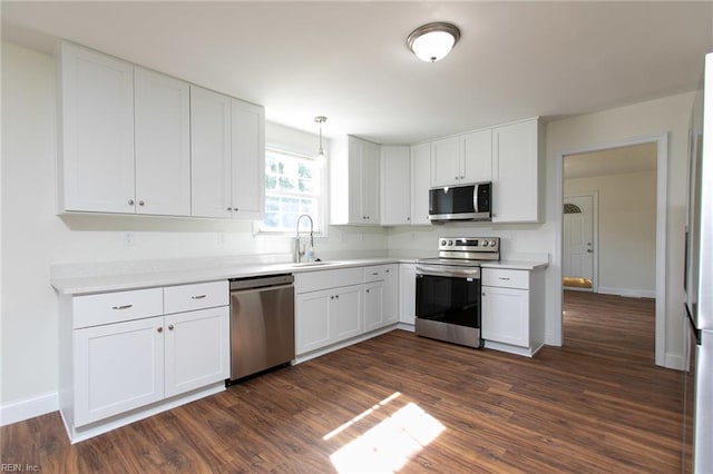 kitchen with appliances with stainless steel finishes, dark hardwood / wood-style flooring, white cabinetry, and sink