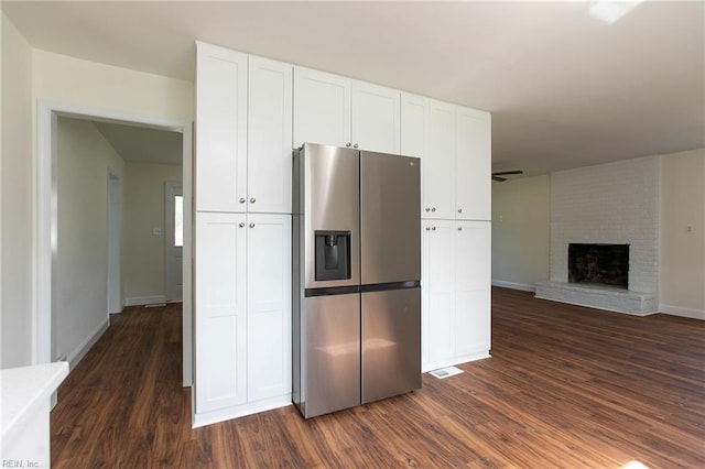 kitchen featuring a fireplace, dark hardwood / wood-style flooring, white cabinetry, and stainless steel refrigerator with ice dispenser