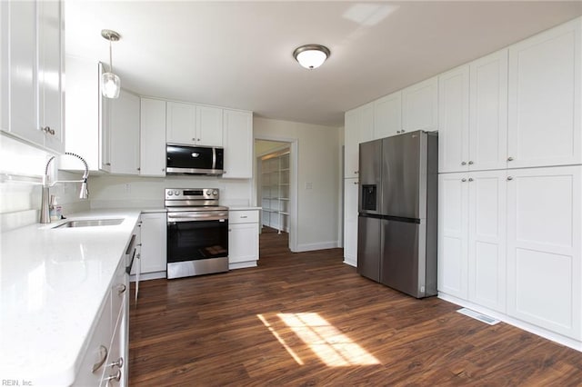 kitchen featuring stainless steel appliances, dark wood-type flooring, sink, decorative light fixtures, and white cabinetry