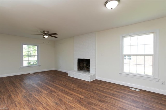 unfurnished living room with a fireplace, dark hardwood / wood-style floors, plenty of natural light, and ceiling fan